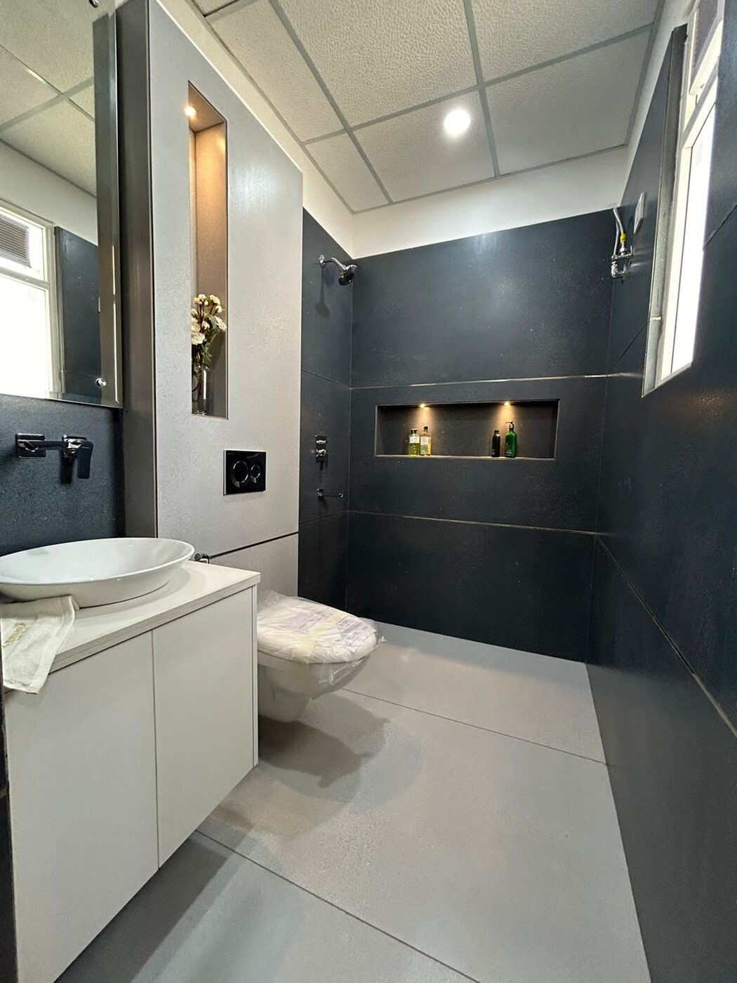 Bathroom with a charcoal feature wall, shower niche and wall-hung WC — Absolute Residency, Sector 92 Mohali