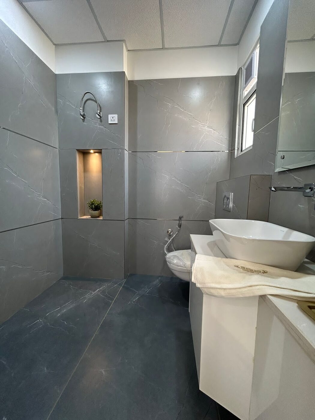Bathroom in grey marble-effect tile with a counter basin and shower area — Absolute Residency, Sector 92 Mohali