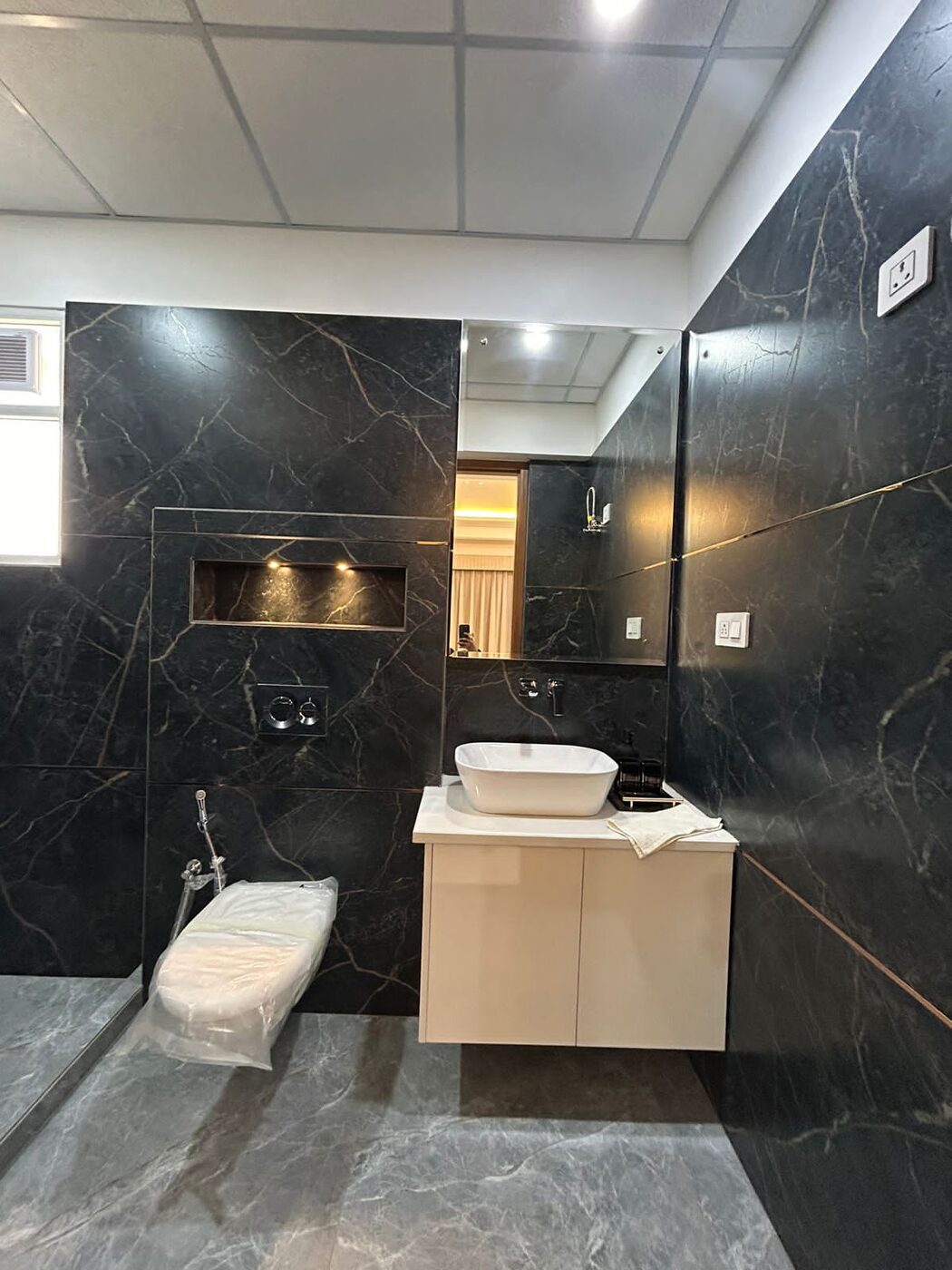 Bathroom in dark marble-effect tile with a counter basin and mirror cabinet — Absolute Residency, Sector 92 Mohali