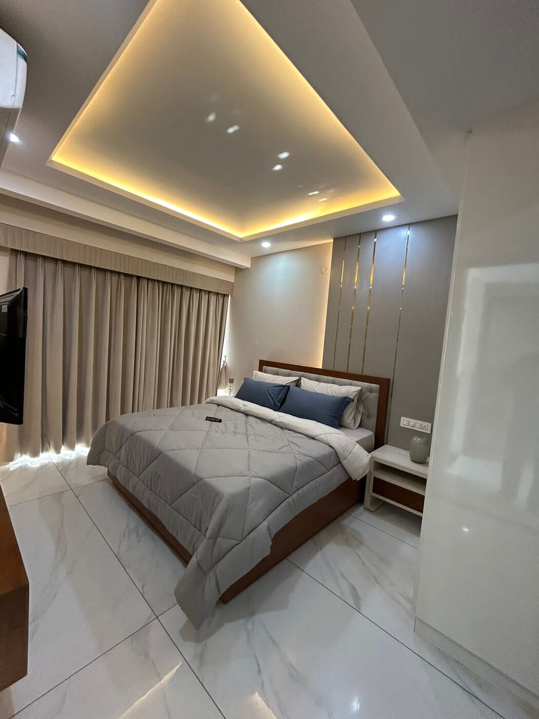 Bedroom with recessed cove lighting and a wall-mounted television — Absolute Residency, Sector 92 Mohali