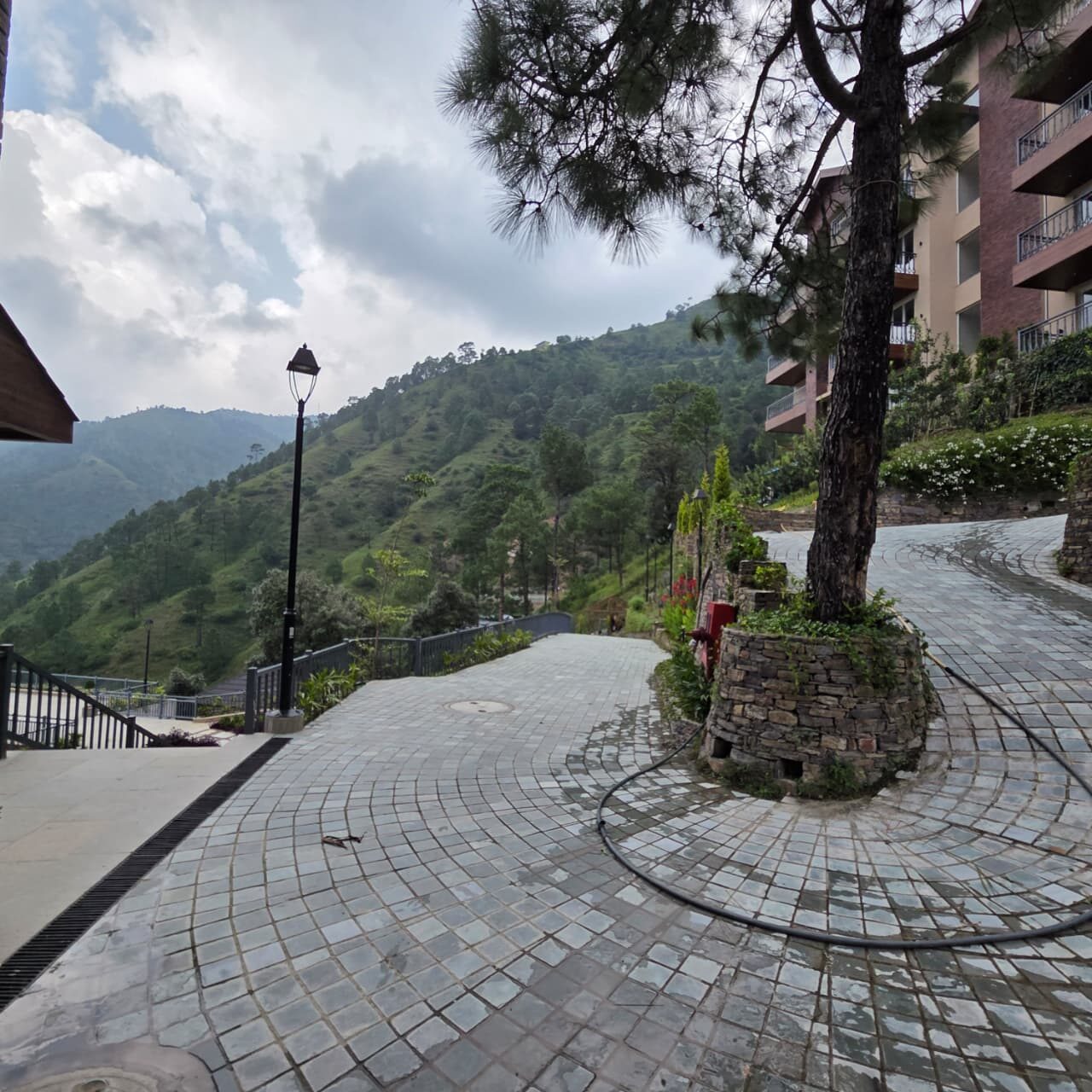 Paved walkway and lamp standard between buildings, hills beyond — Himachal Pradesh