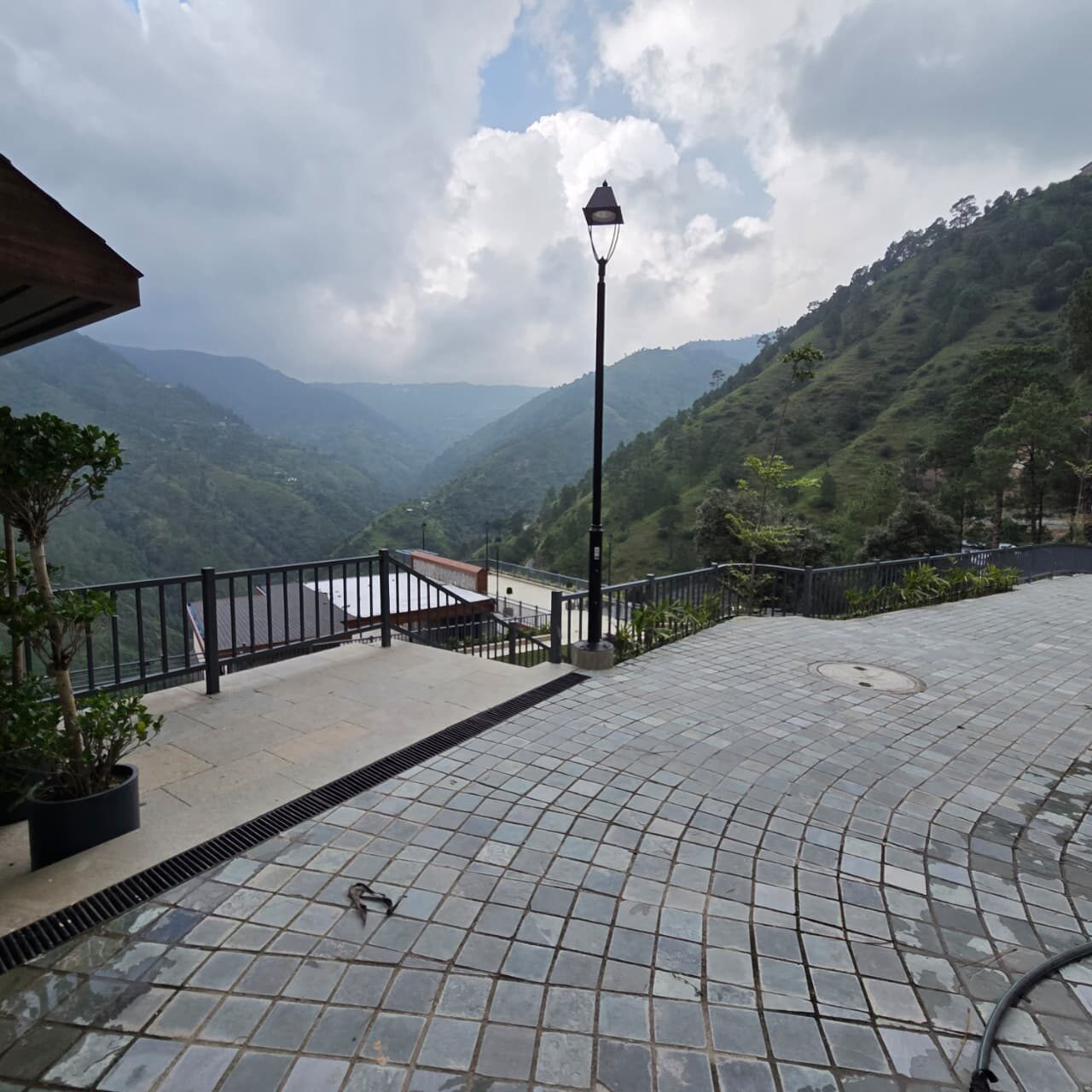 Paved terrace with a lamp standard, looking down a wooded valley — Himachal Pradesh