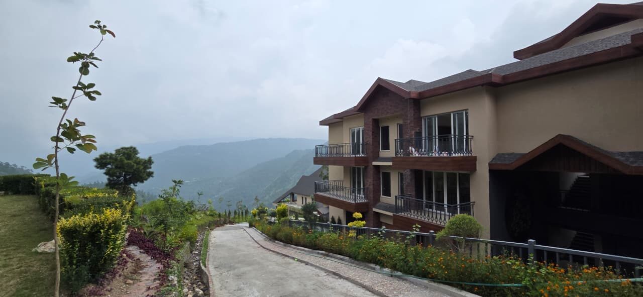 Low-rise residences with shingle roofs along an internal road — Himachal Pradesh